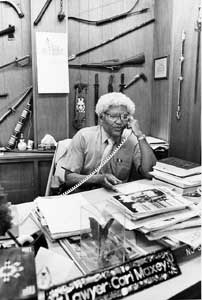 Maxey in his law office, walls bristling with weapons